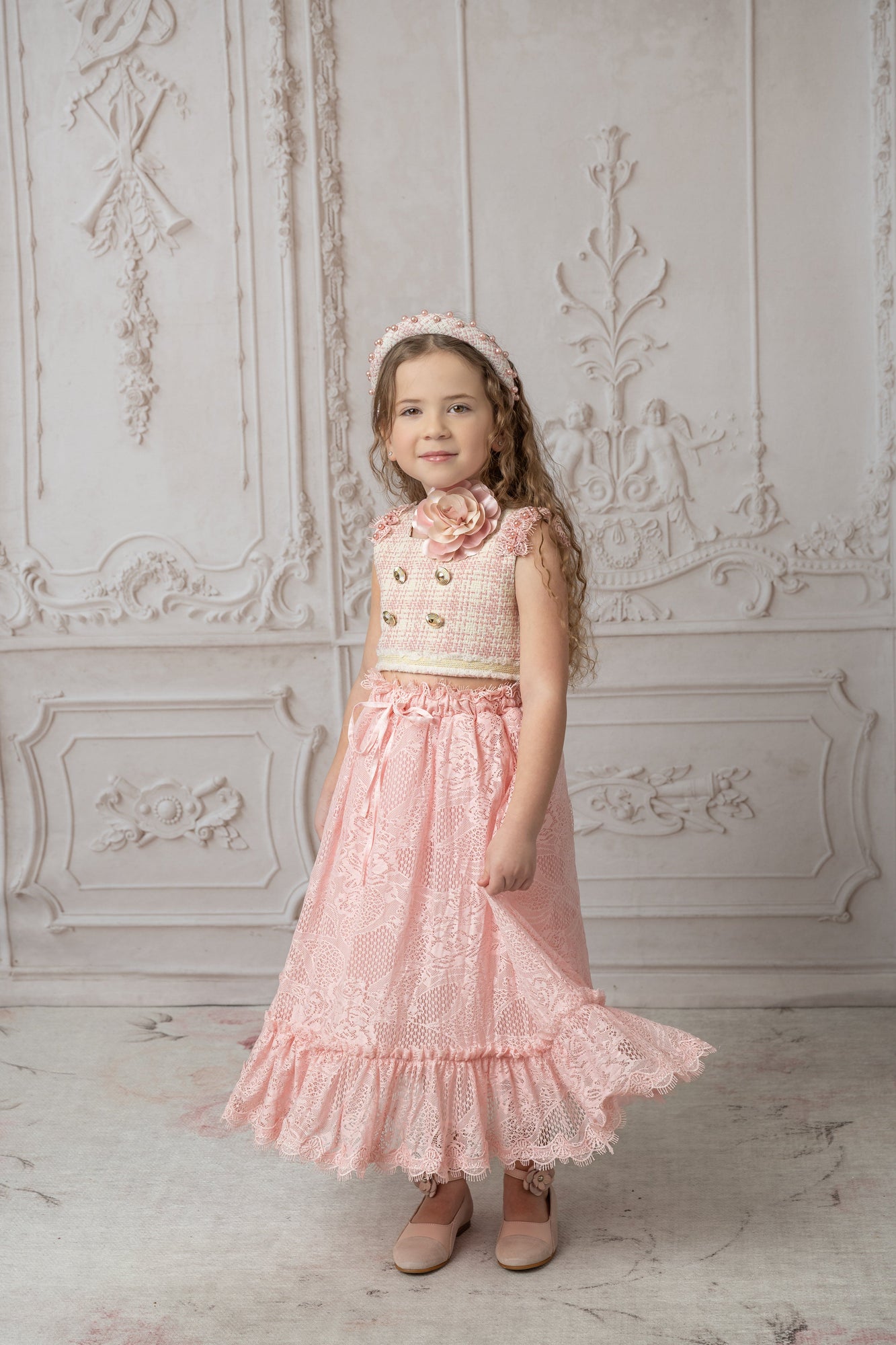 Girl with pink and beige tweed top with gold button details paired with a pink lace and ruffle skirt