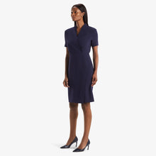 Side image of a woman standing wearing theTory Dress in dark iris