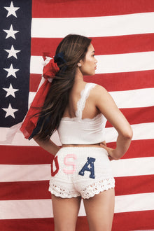 White crochet fabric shorts with a ribbed crochet waistband with a tassel drawcord at center front.