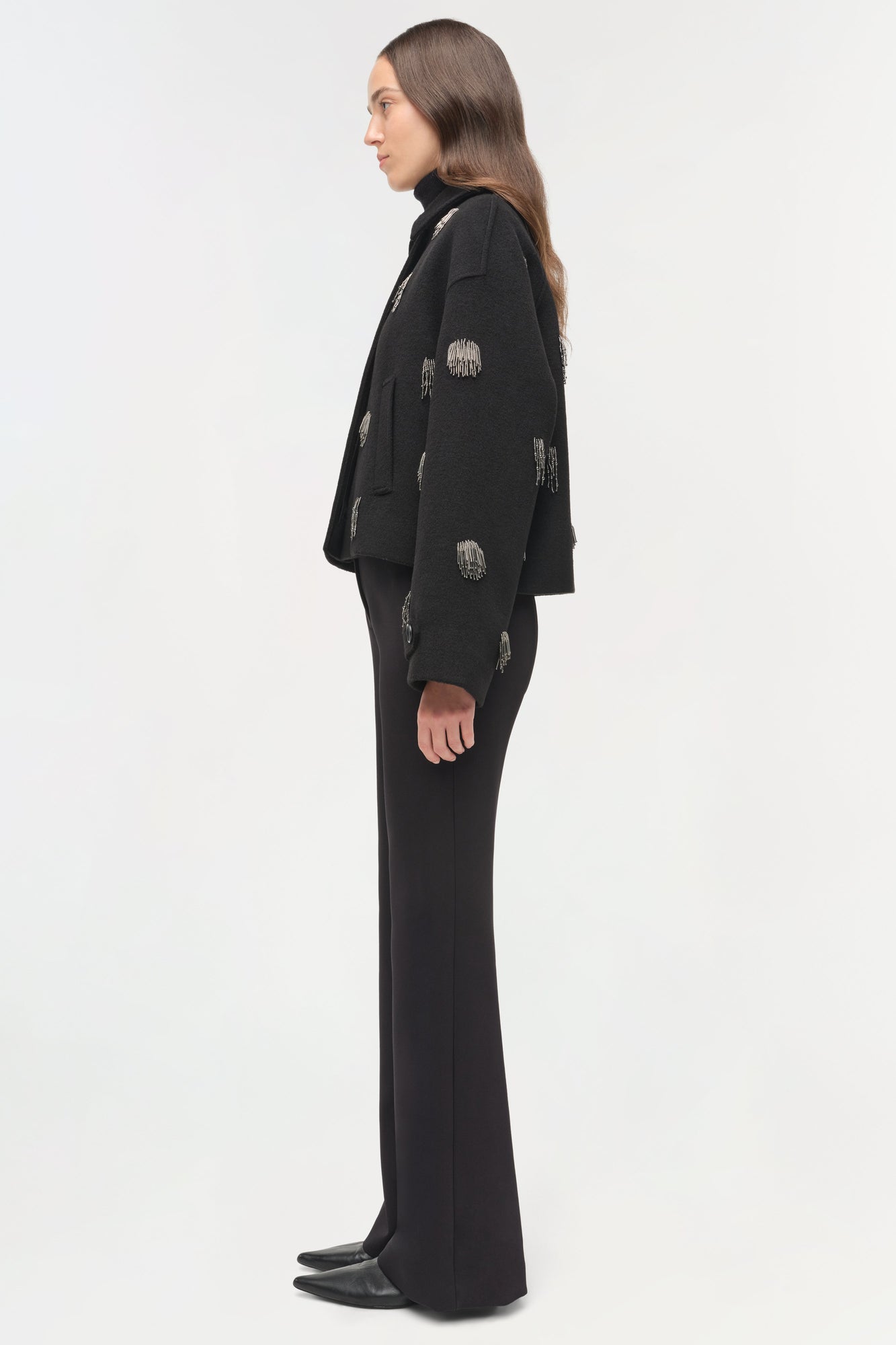 Black jacket with silver beaded embellishments scattered across the front and sleeves, worn over matching black pants.