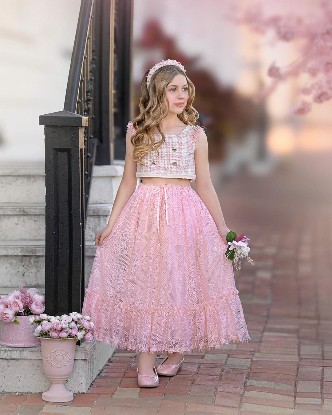 Girl wearing a beige and pink tweed top with a matching pink lace ruffle skirt 