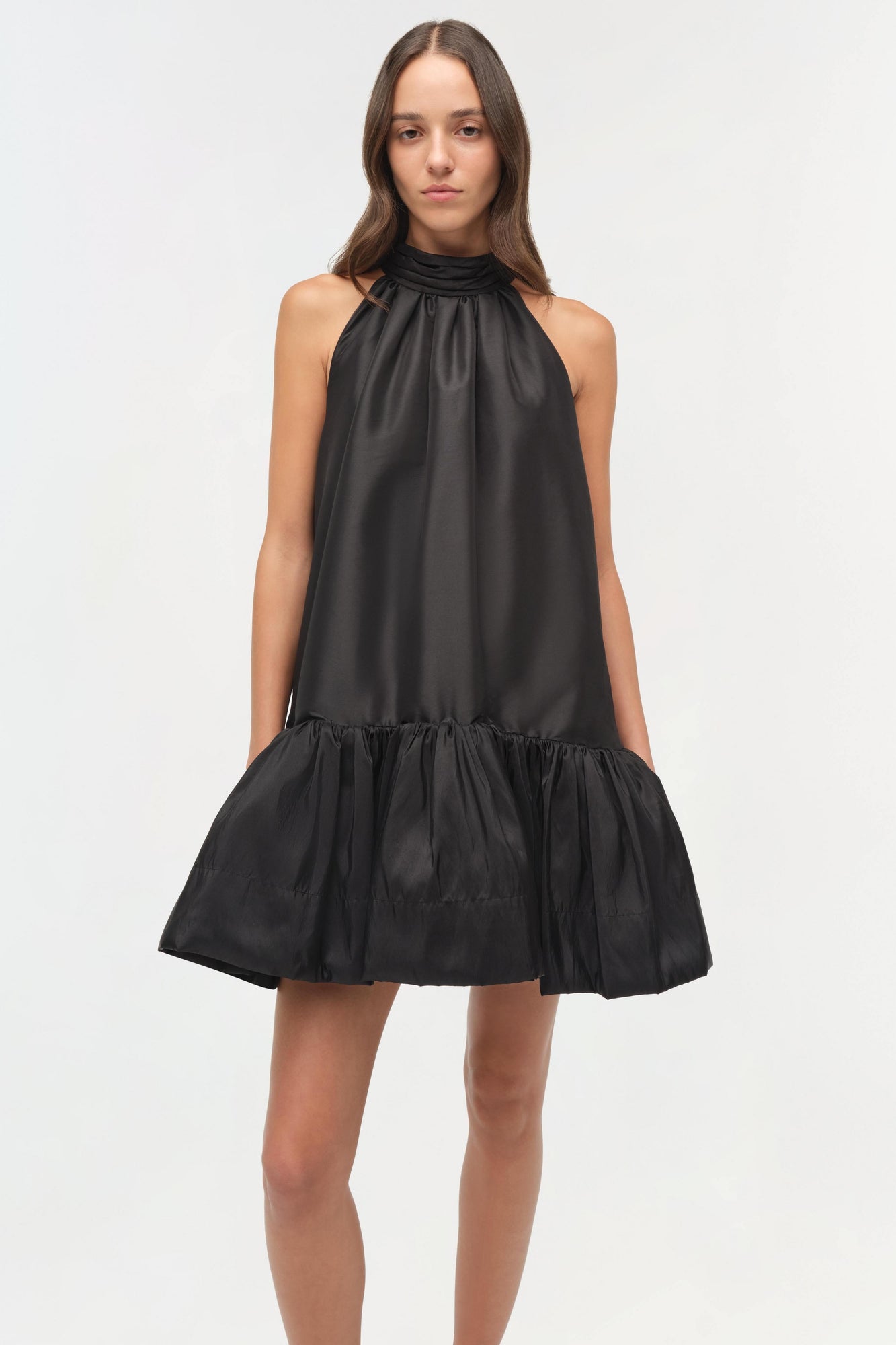 Black sleeveless halter mini dress with gathered neckline and voluminous pleated skirt.