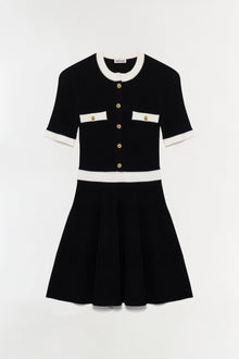 Black ribbed knit mini dress with cream collar, cuffs, and waistband, featuring gold buttons and chest pockets.
