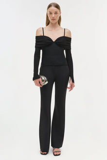 Black off-shoulder top with long sleeves, twist front detail, and thin shoulder straps on model.
