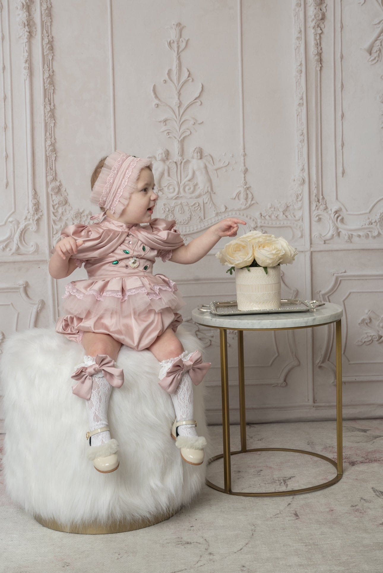 Baby girl wearing pink ruffle romper styled for a special occasion 
