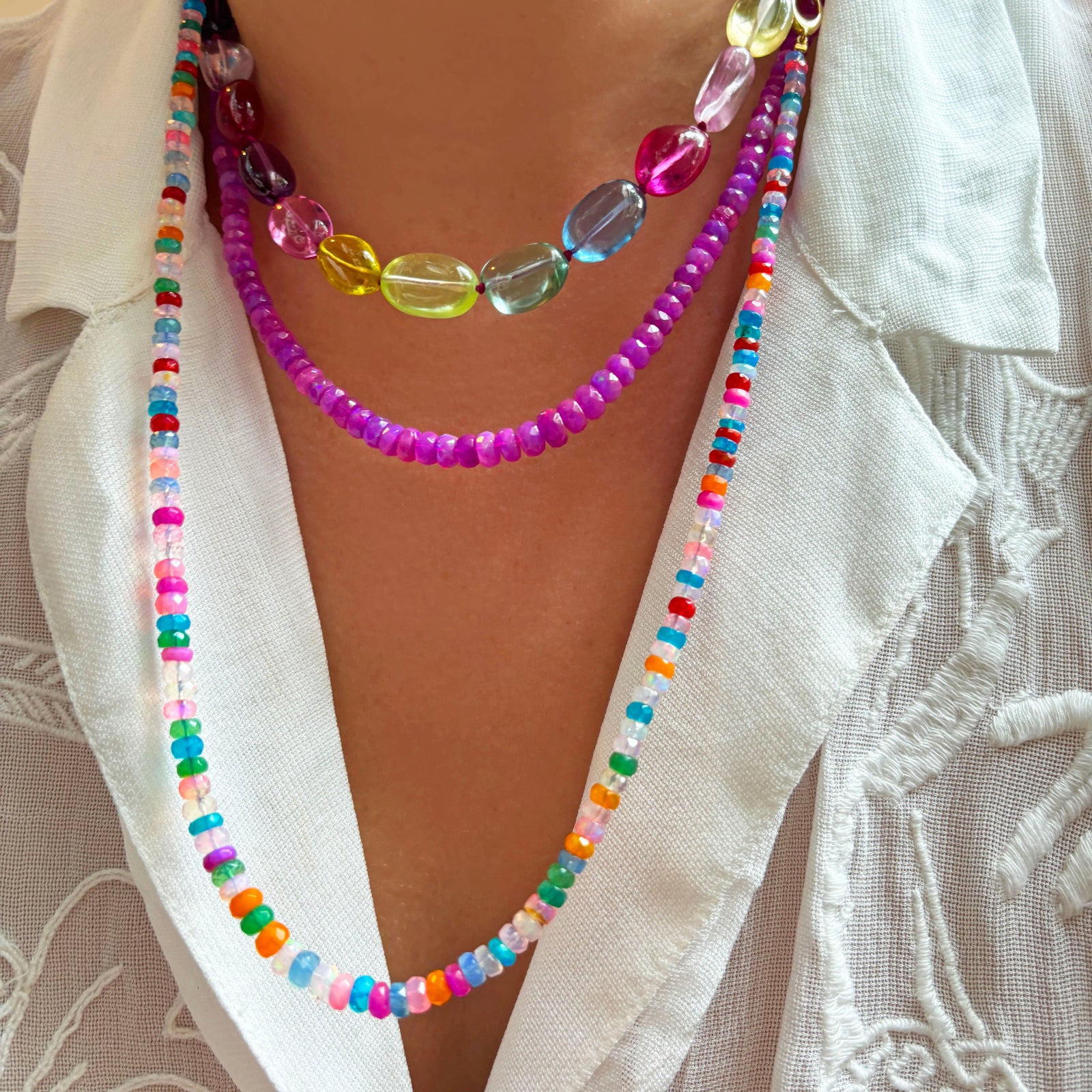 A double length of tie dye opal necklaces layered with faceted fuchia opals on the neck.
