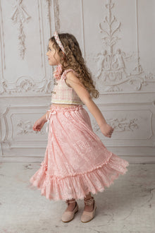 A girl wearing a pink and beige tweed top with a pink ruffle lace skirt