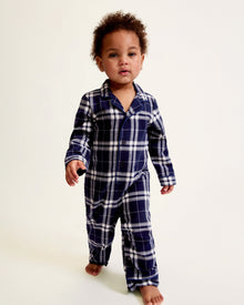 The Baby's Brushed Twill Classic Romper in Oxford Tartan is a full-length, long-sleeve children's onesie featuring a navy, white, and gray plaid pattern with a button-up front, collar, and snap leg closures.