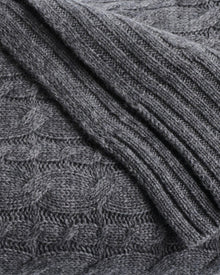 Close-up of Petite Plumes Cashmere Cable Knit Throw in Dark Grey featuring a ribbed texture on the right and a subtle diamond pattern on the left. The soft, thick material is perfect for crafting cozy sweaters or stylish home decor, making it a giftable choice.