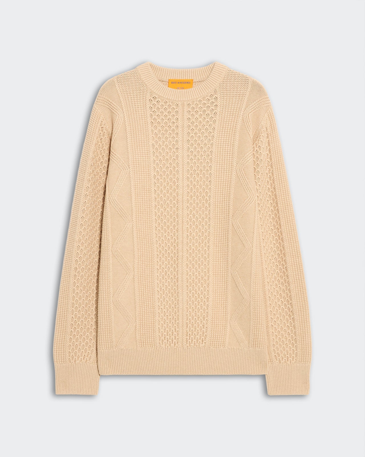 Allday Cable Crew - Sandstone, a light beige cable-knit sweater featuring intricate textured patterns, ribbed cuffs, collar, and hem, laid flat on a soft gray background.