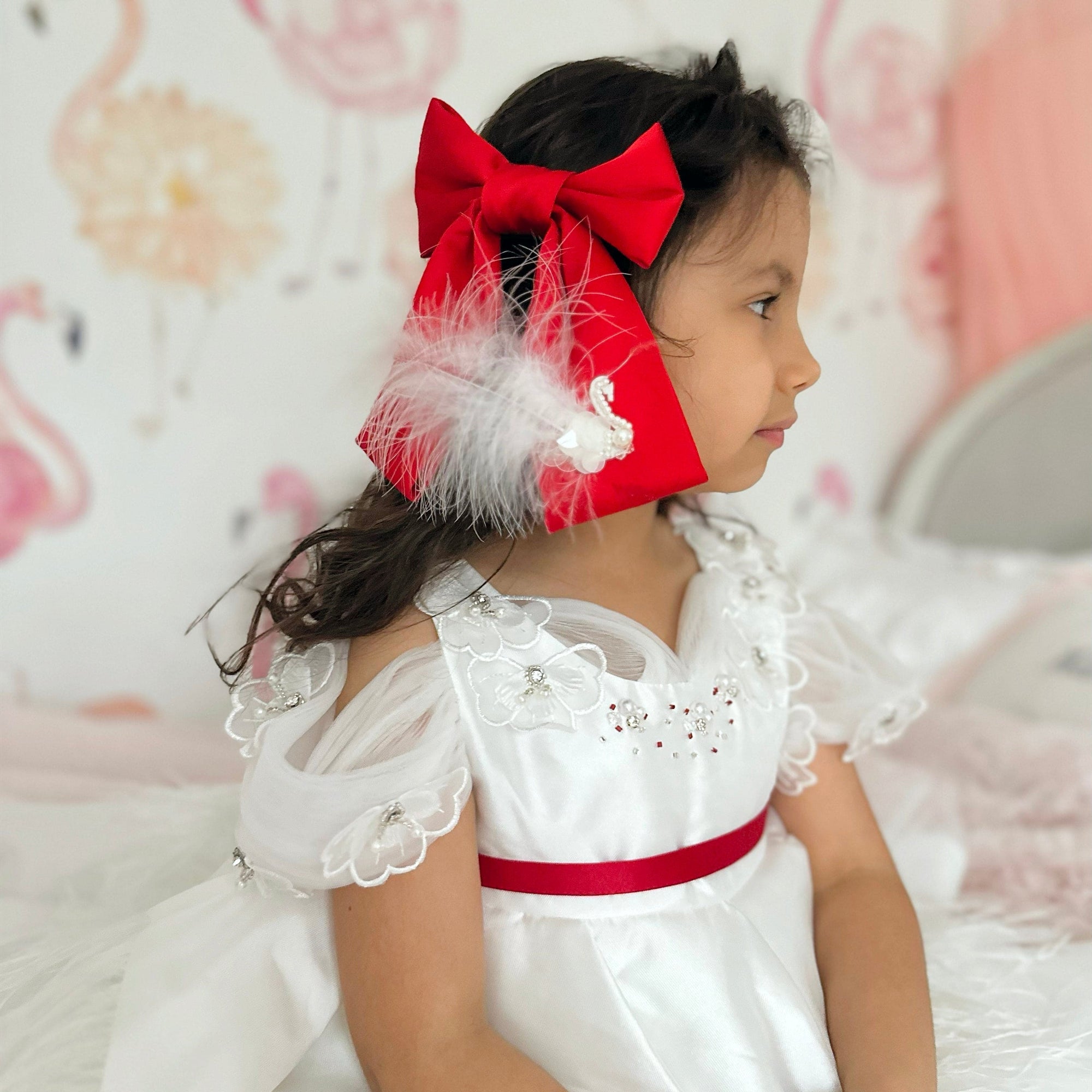 Girl wearing large red satin bow with white feather embellishment
