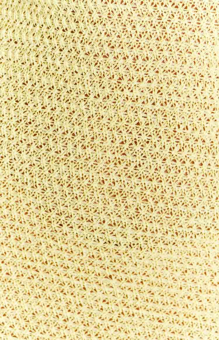 Close-up of the yellow crochet knit fabric with a geometric pattern of the maxi dress
