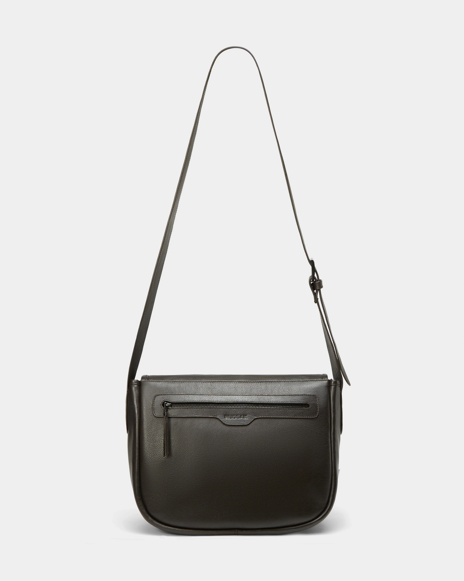 The Rudsak GRAYSON - 8324512 Espresso is a dark brown leather crossbody bag with a long adjustable strap, front zipper pocket, and minimalist design, shown against a plain white background.