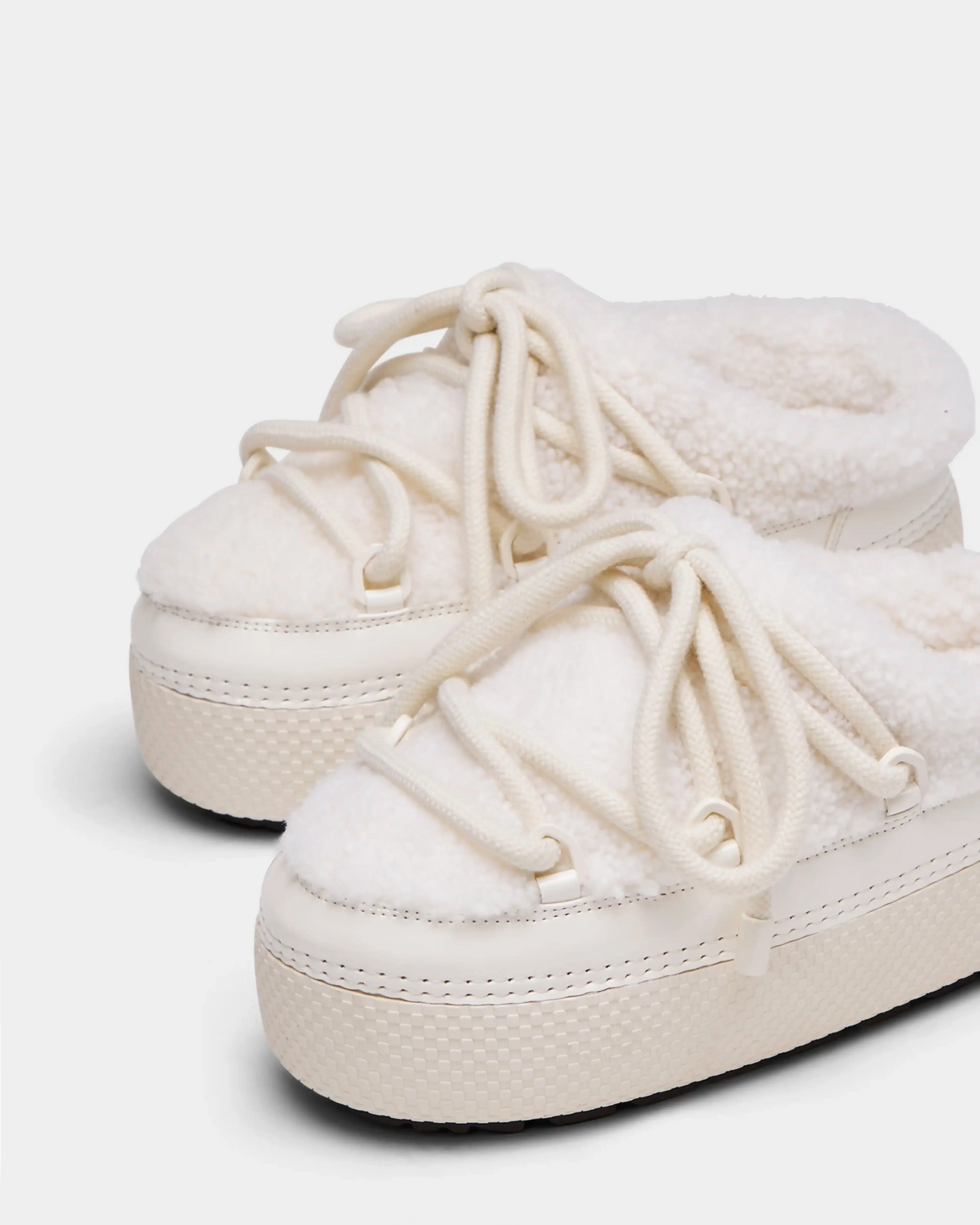 The Rudsak HARRIET - 8224519 Iceland sneakers feature an off-white, fleece-lined design with thick textured soles and chunky laces. These cozy shoes resemble fashionable faux shearling slippers, shown on a white background.