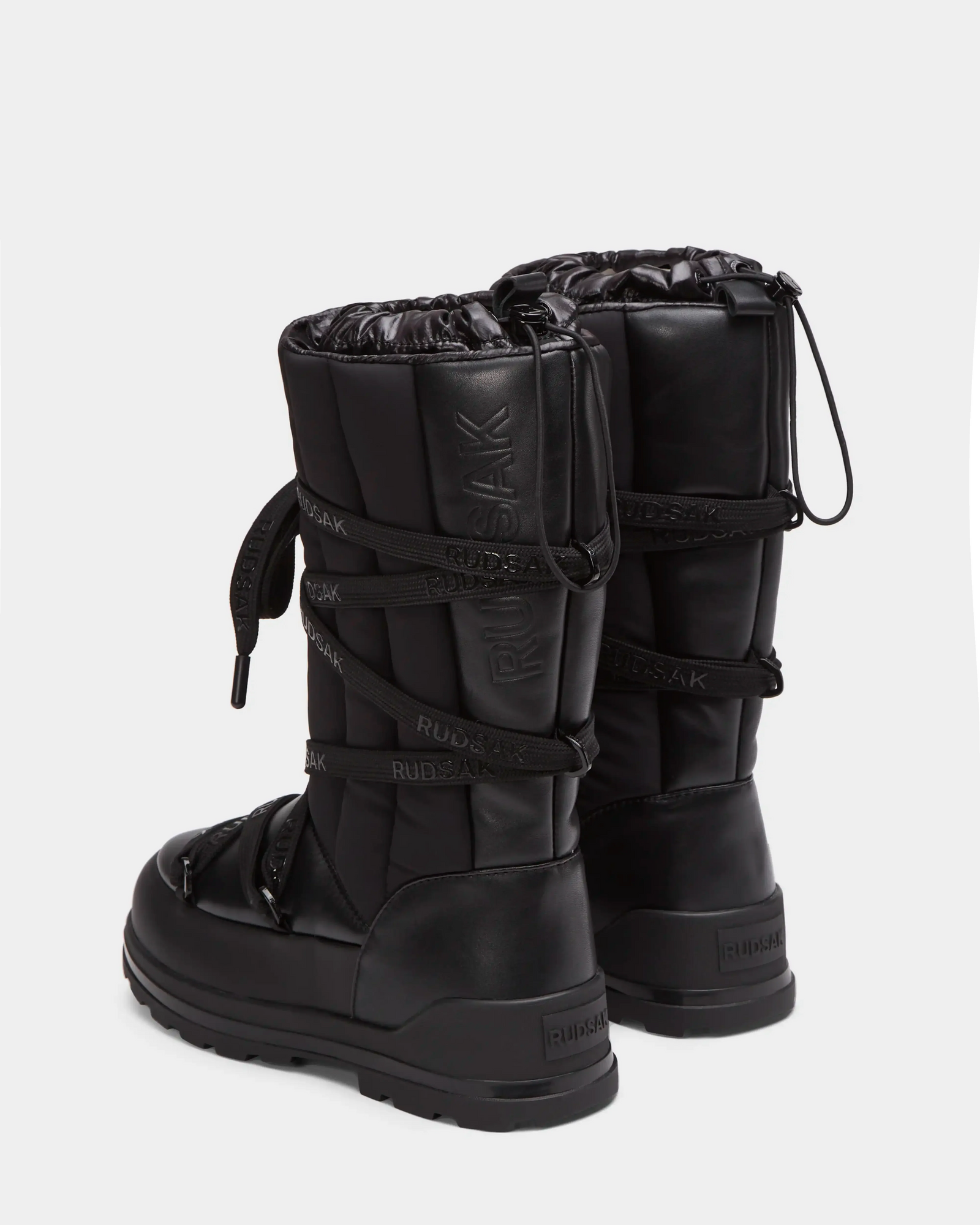 The RODIN - 8224502 Black womens winter boots by Rudsak feature insulation, thick anti-slip soles, drawstring closures, and branded wraparound straps, shown from the back and side on a white background.