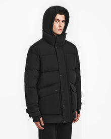 A man wearing the ROKO - 6124510 Black men’s quilted down parka by Rudsak.