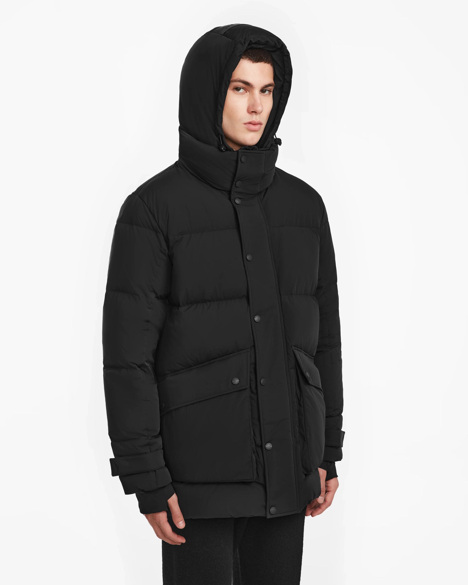 A man wearing the ROKO - 6124510 Black men’s quilted down parka by Rudsak.