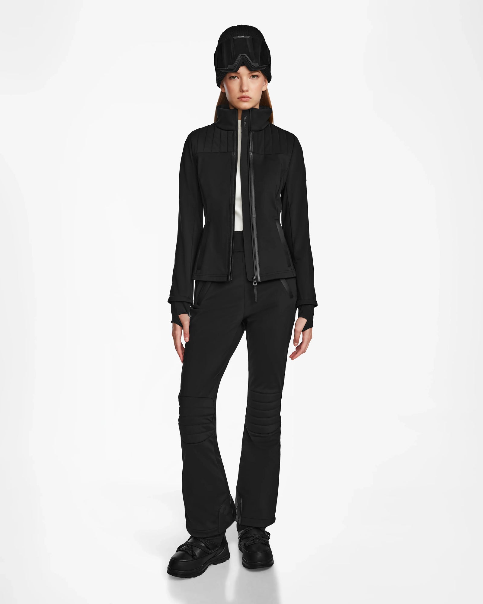 A woman in the Rudsak ROSALIE - 8124784 Black fitted ski jacket featuring RECCO rescue technology, dressed all in black.