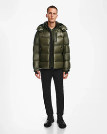 A man faces forward wearing the Rudsak VINCE S - 6124560 Loden Green men’s down puffer jacket, styled with black pants, shirt, and boots—ideal for cold-weather layering—set against a plain white background.