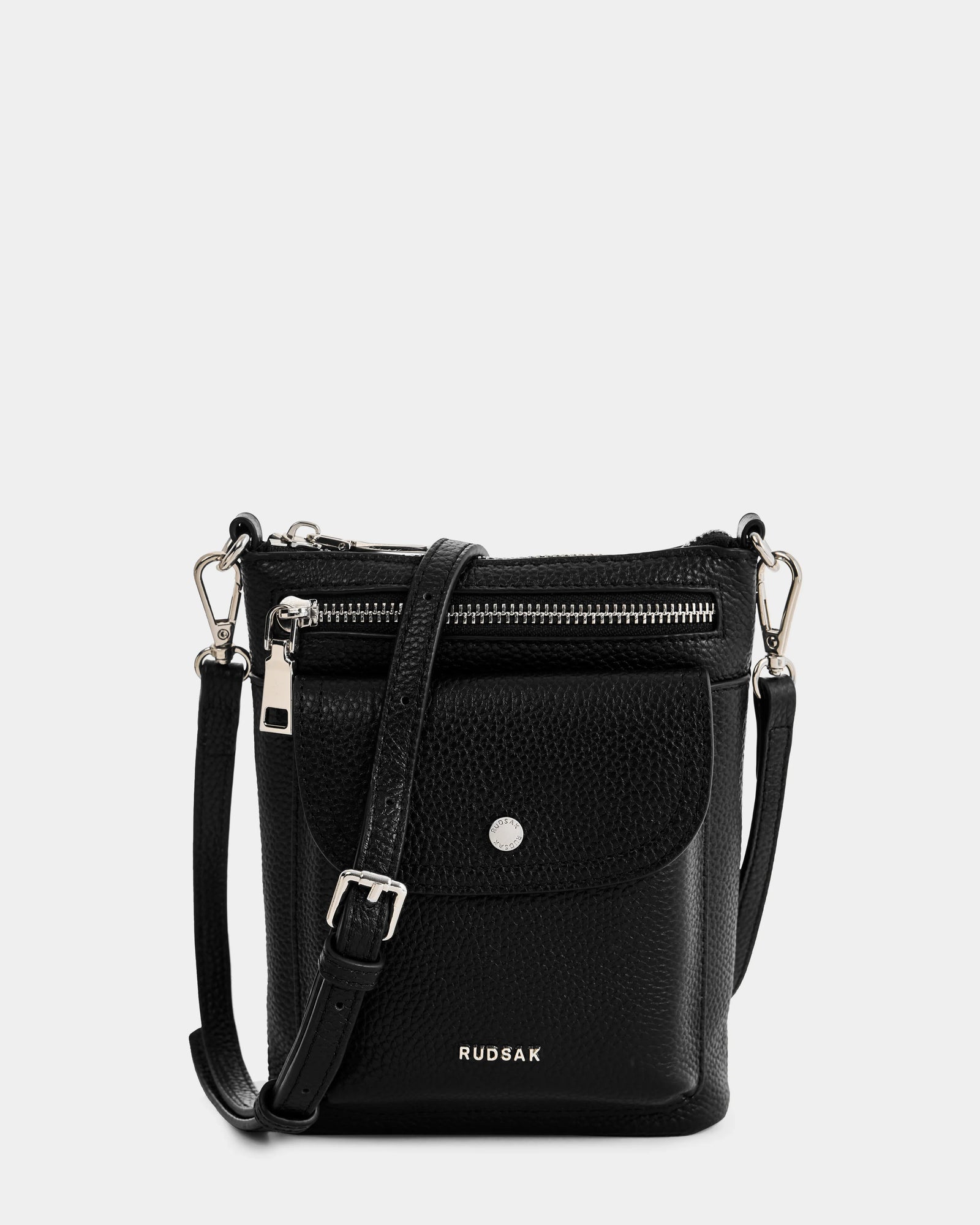 The Rudsak LILA - L325513 Black is a small women’s crossbody leather bag with pebbled leather, a front zip pocket, flap pocket with snap button, silver logo, and an adjustable strap with sleek silver hardware.
