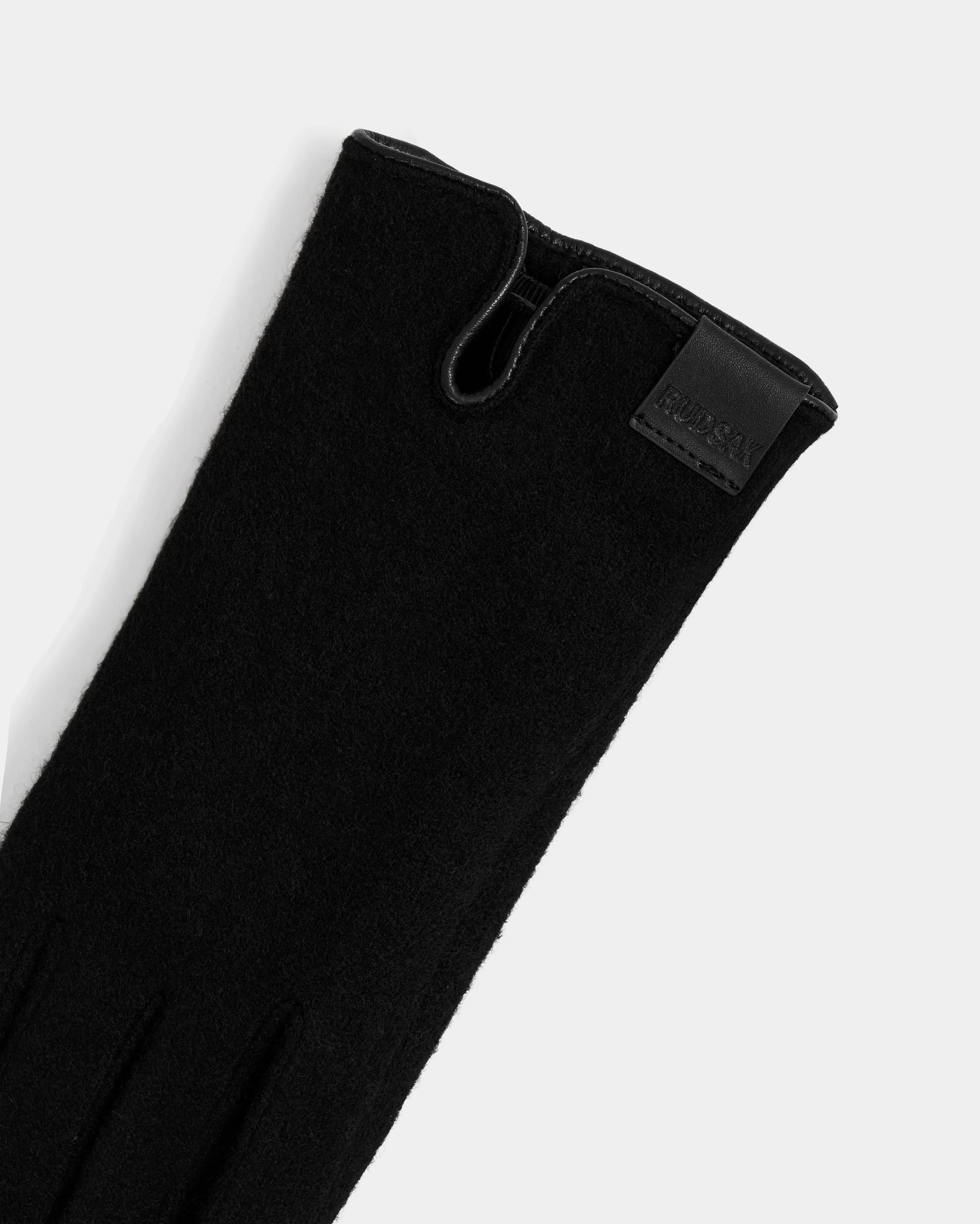 A close-up of the OLGA - L425541 Black women’s glove by Rudsak, featuring soft wool-cashmere lining, elegant stitching, a subtle slit, and a leather patch with embossed text—an essential for cold weather.