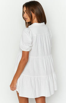 Rear view of a white linen tiered dress with puffed short sleeves and gathered tiers
