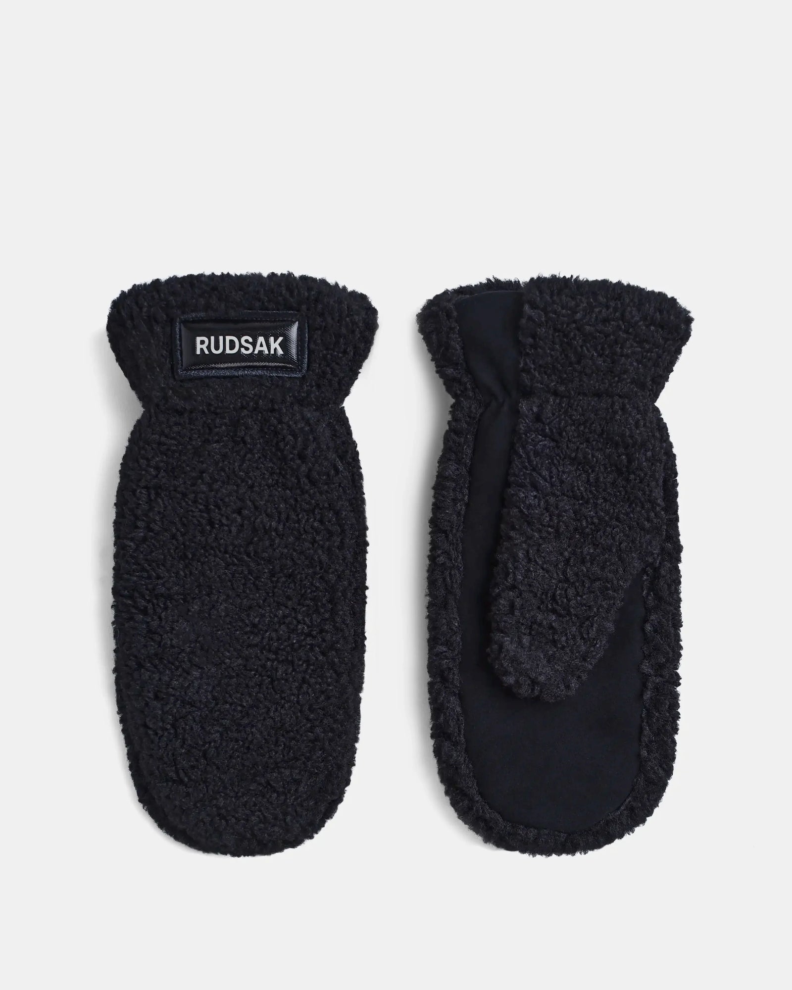 A pair of Rudsak SUSAN S - 8423511 black faux fur mittens with a soft texture is shown on a white background. One mitten displays the brand label on the cuff, while the other reveals the thumb and palm side.
