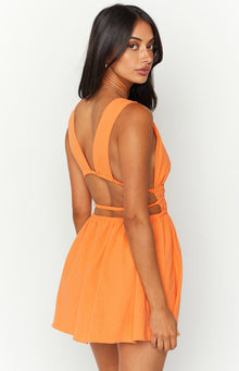 Close-up of the orange crinkle mini dress showing the deep V-neckline, cutout detail, and shirred waist