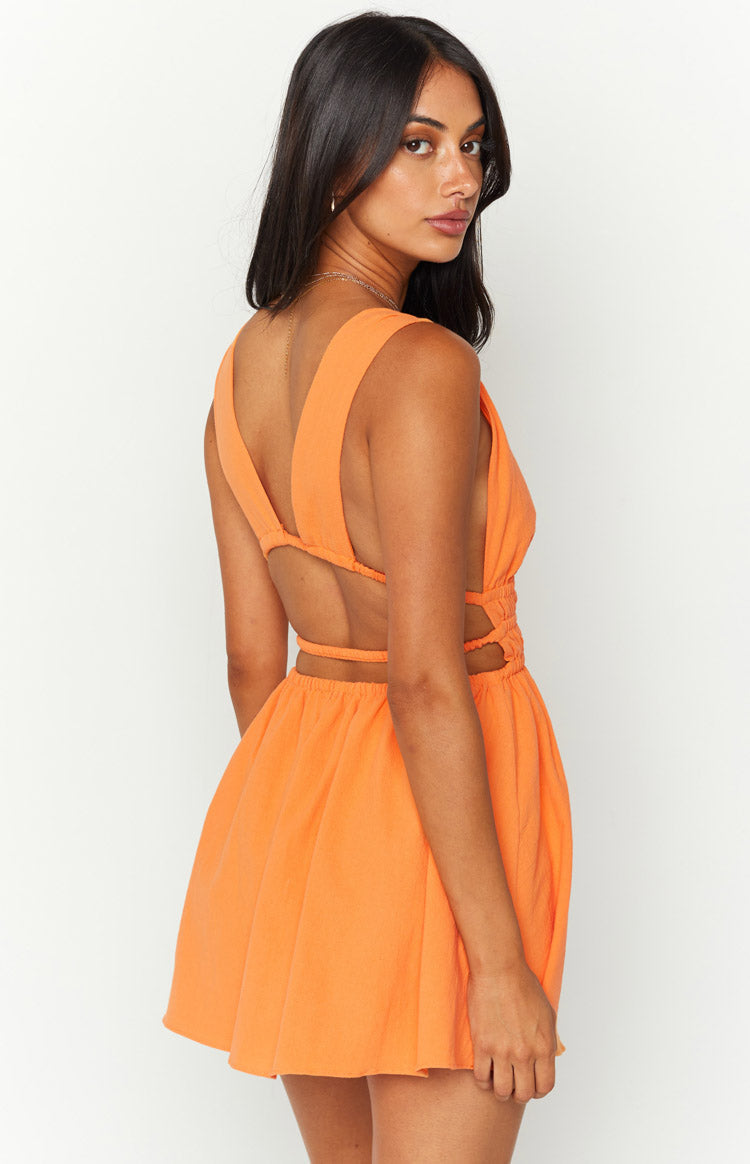 Close-up of the orange crinkle mini dress showing the deep V-neckline, cutout detail, and shirred waist