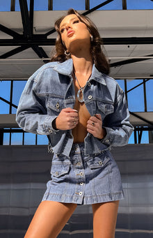 Rear view of a mid-wash denim mini skirt with prominent vertical seam detailing on the back