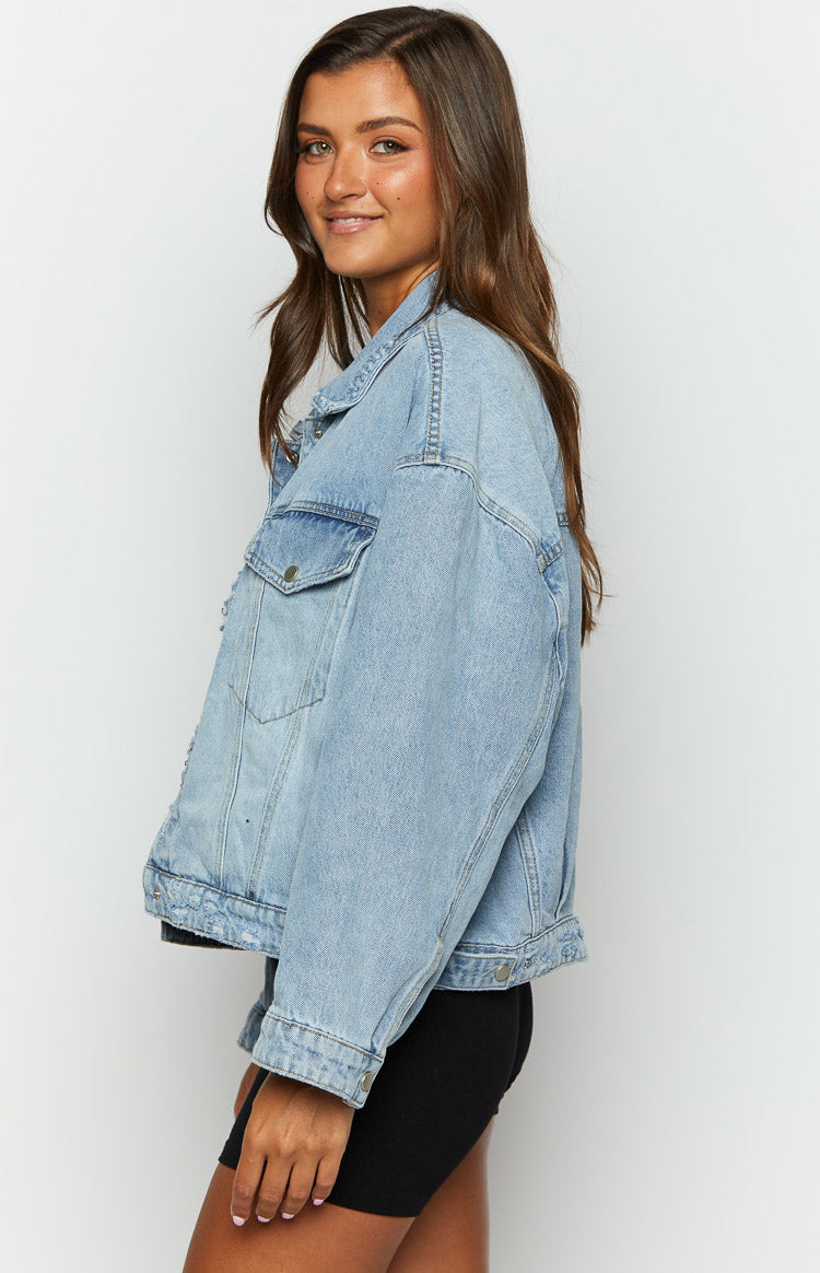 Side view of a light wash oversized denim jacket with dropped shoulders and a buttoned chest pocket