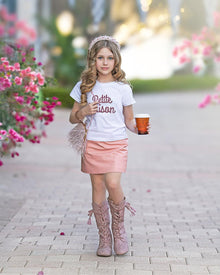 Girl walking in a pink vegan leather skirt with a sleek faux leather finish, functional pockets, and flattering above the knee cut