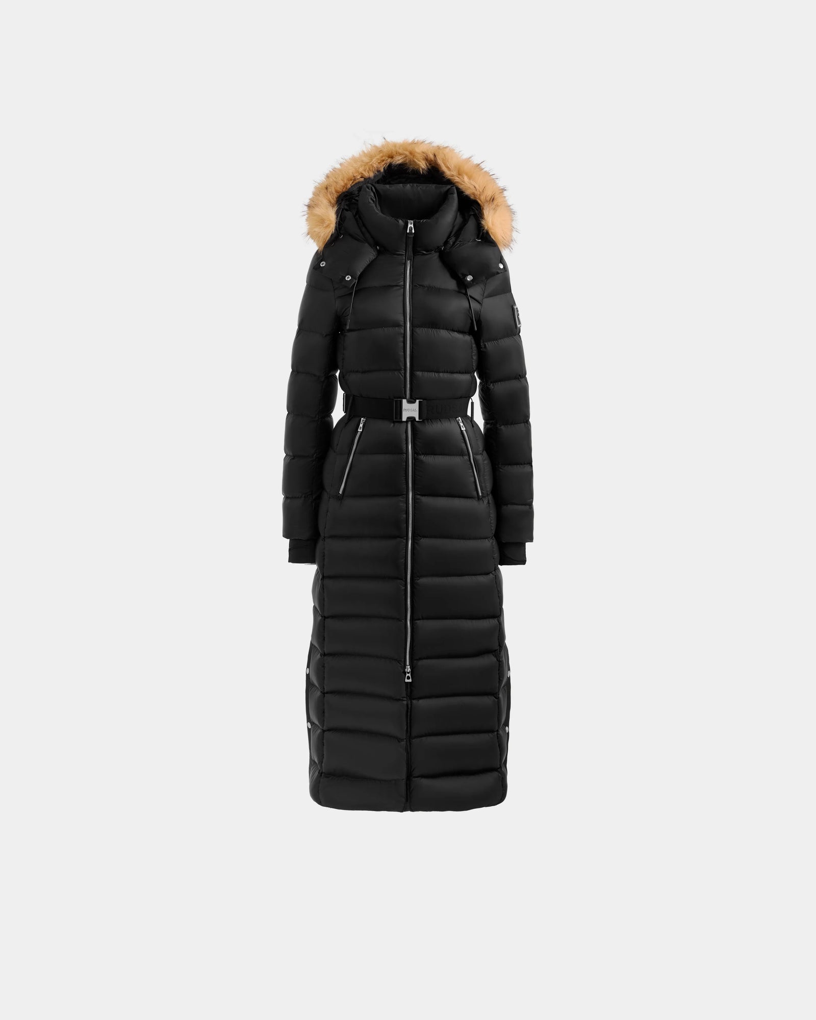The Rudsak LILITH L - L125528 Black is a long black puffer coat with a faux fur-trimmed hood, belted waist, full-length front zipper, horizontal quilting, and two side zippered pockets, shown on a plain light gray background.