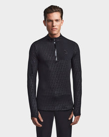 A man faces forward wearing the Rudsak WARREN - 6523502 Black Pattern men’s fitted stretch top with a zip-front mock neck and subtle geometric design, standing against a plain background with hands relaxed by his sides.