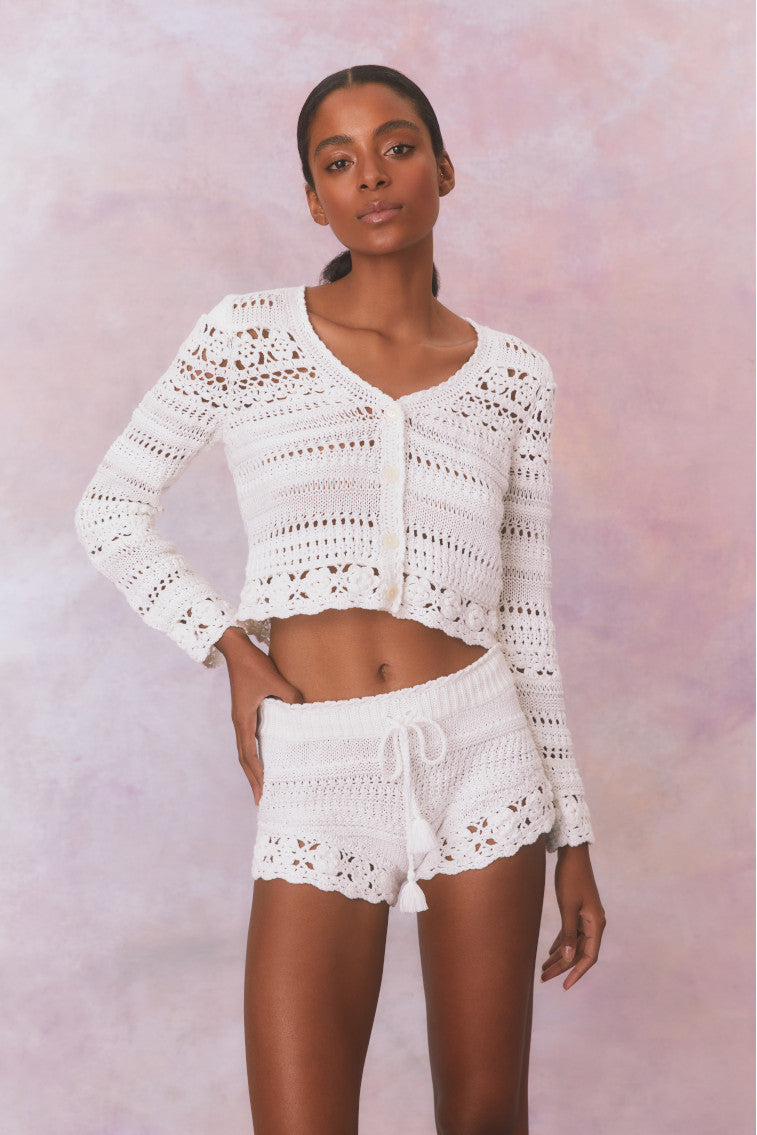White crochet fabric shorts with a ribbed crochet waistband with a tassel drawcord at center front.