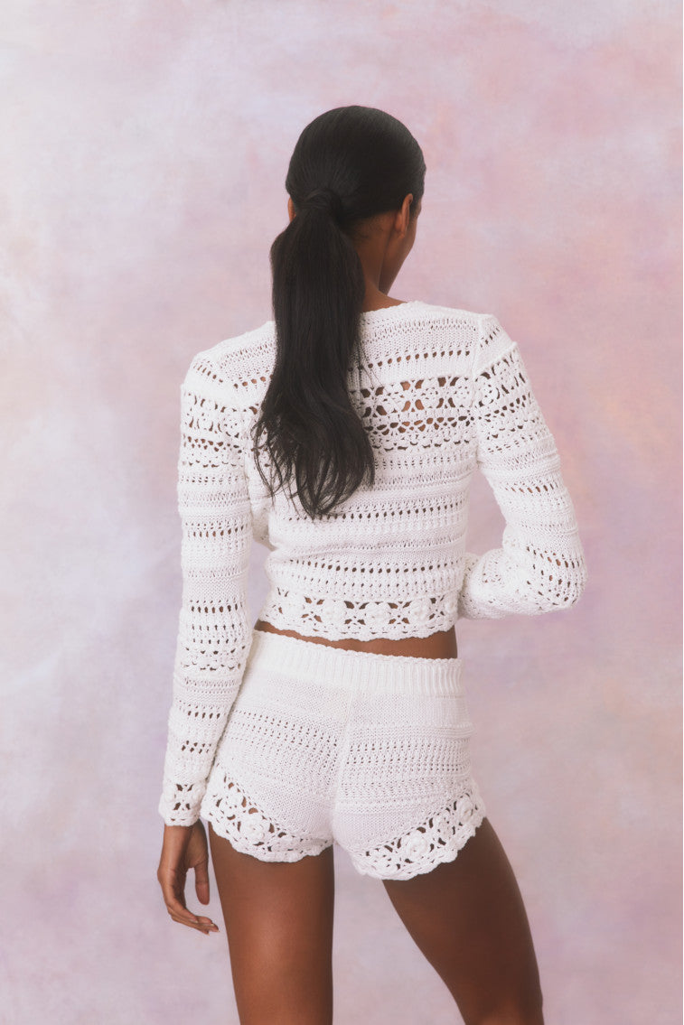 White crochet fabric shorts with a ribbed crochet waistband with a tassel drawcord at center front.