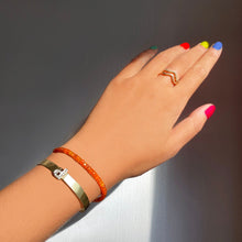 Shimmering beaded bracelet made of faceted opals in shades of orange on a gold linking lobster clasp styled on a wrist with Diamond P Letter Bangle