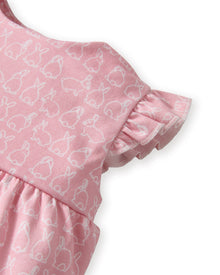 Baby's Pima Isla Play Romper in Hoppy Days Pink features flutter sleeves, ruffled leg openings, a gathered waist, and an allover white bunny outline print. Shown laid flat on a white background.