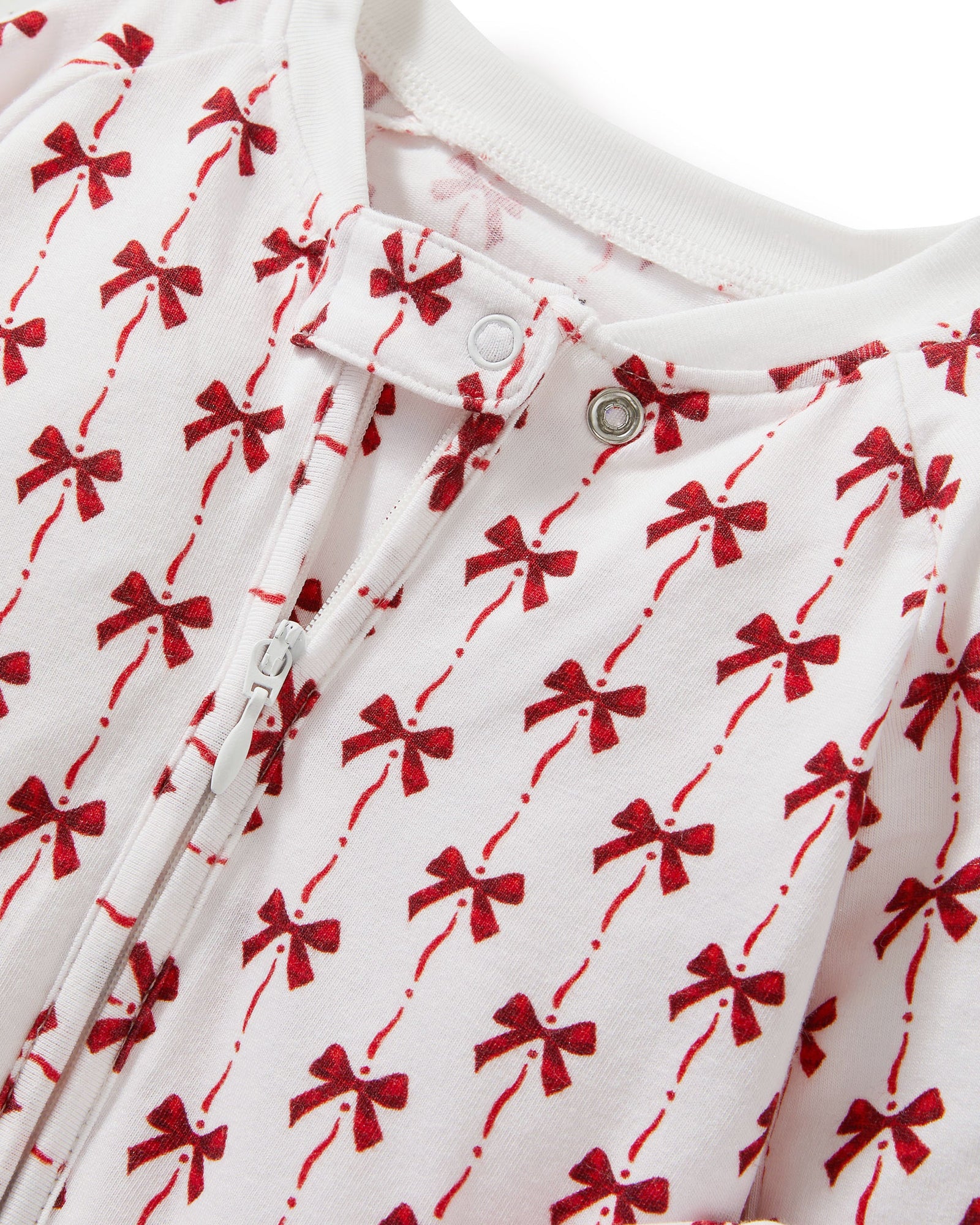 The Baby's Pima Peekaboo Romper in Blissful Bows is a white long-sleeve onesie with cuffs, adorned with festive red bows and a convenient back zipper.