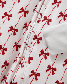 The Baby's Pima Peekaboo Romper in Blissful Bows is a white long-sleeve onesie with cuffs, adorned with festive red bows and a convenient back zipper.
