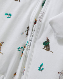 The Baby's Pima Peekaboo Romper in Jingle Paws is a white, long-sleeve onesie with a front zipper, decorated with colorful dogs and green bones. The left leg appears slightly folded over.