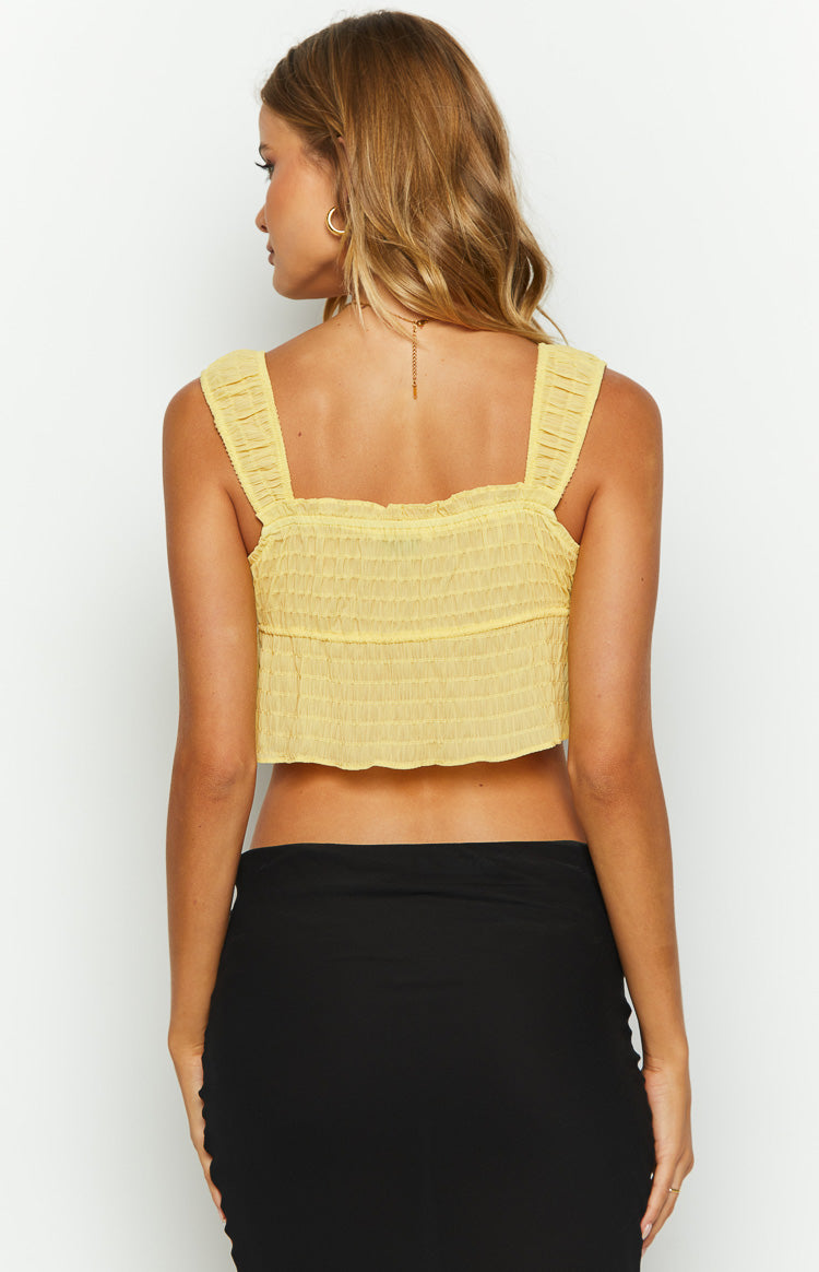 Close-up of the yellow smocked crop top showing the tie-front detail and ruffled neckline