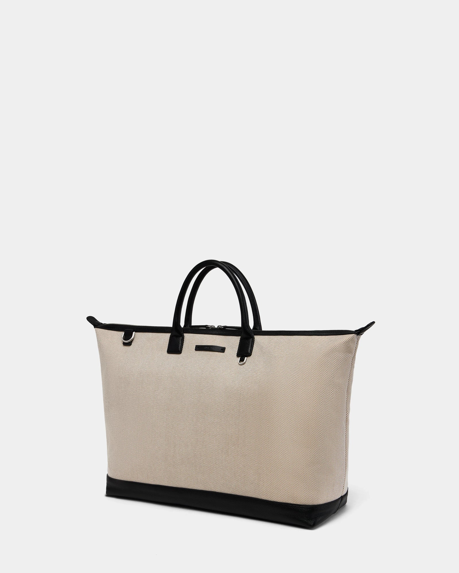 The Rudsak DUBLIN - 9324514 Vanilla is a large beige canvas leather tote with black handles, trim, and base—perfect as a unisex weekender—shown against a plain white background.