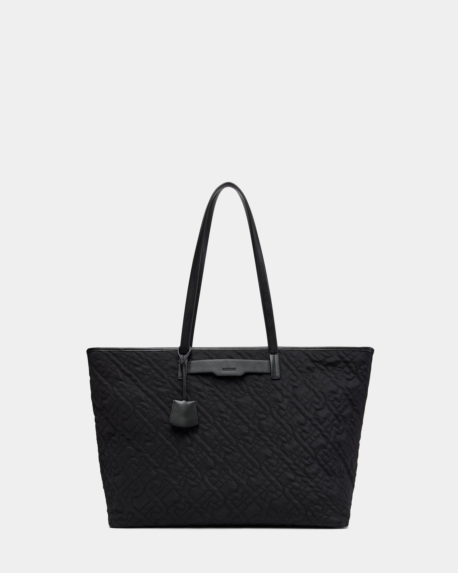 The LIVORNO - L325007 Black tote by Rudsak features two shoulder straps, a subtle embossed pattern, and a leather tag on one handle. This luxury bag is showcased against a simple light background.
