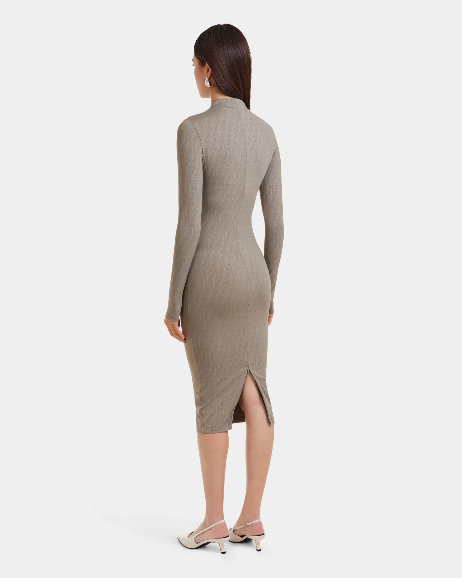 A woman with straight dark hair, white heels, and large earrings stands facing away in the Rudsak MAYLIN - 8523504 Cement Pattern long fitted dress with a back slit. The stretch fabric dress is shown against a plain white background.