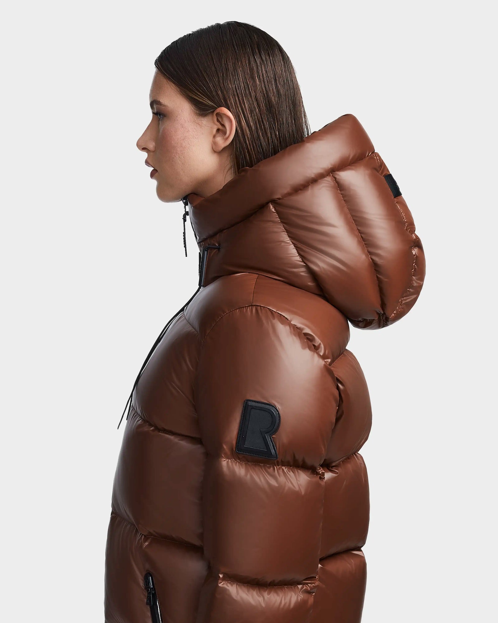 A woman in the Rudsak RITA S - L123527 Cohiba hooded down puffer enjoys cozy warmth and stylish comfort.