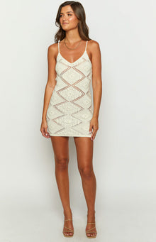 Front view of a cream knit mini dress featuring a V-neck, spaghetti straps, and intricate open diamond knit pattern
