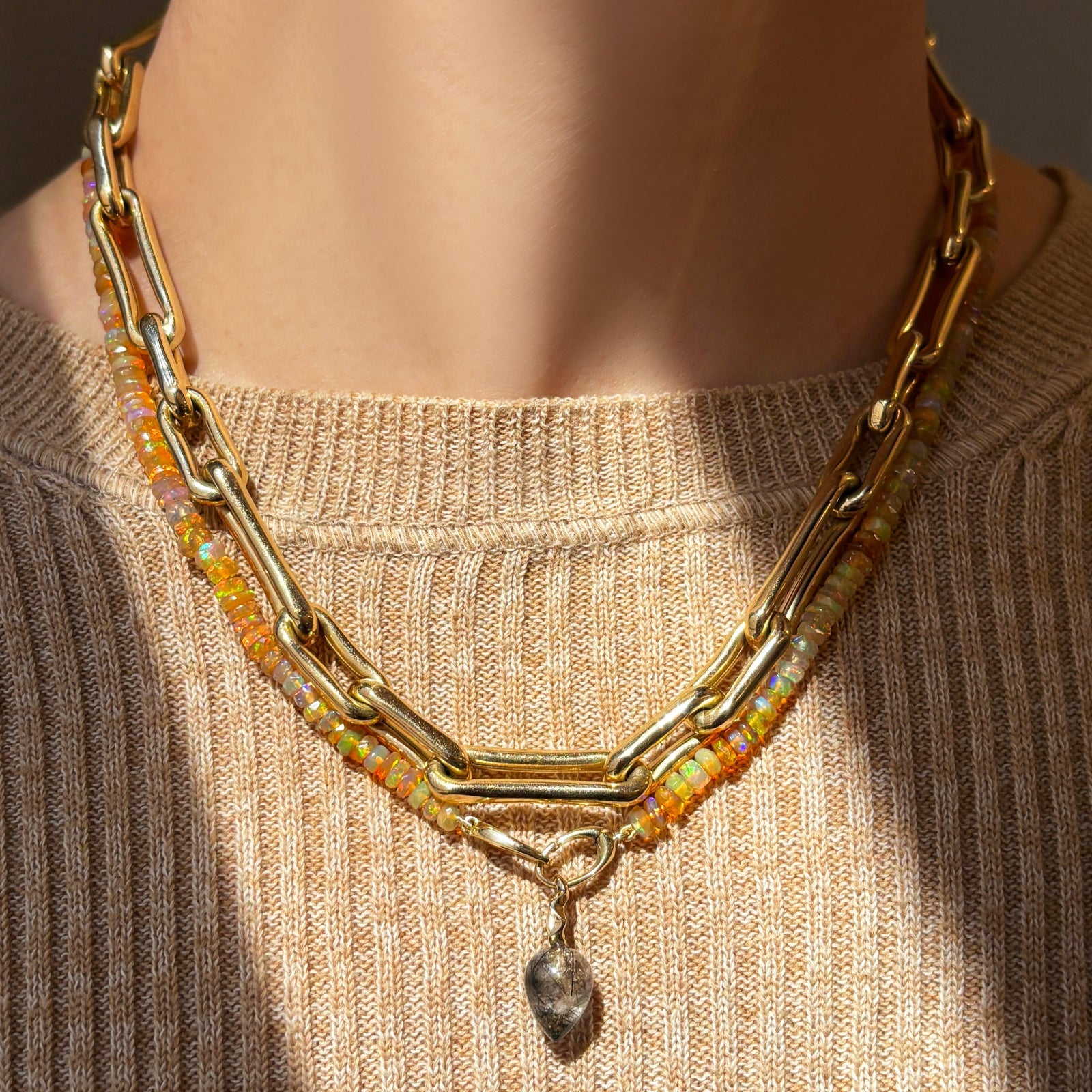 Chunky molten link chain necklace with mercury in retrograde faceted opal necklace with rutilated quartz drop charm over a spring camel knit sweater.