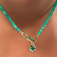 Green faceted opal necklace with emerald knot charm and small emerald charm lock on a person's neck.