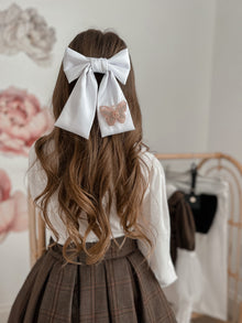 Girl with a large satin bow in her hair embellished with a butterfly detail
